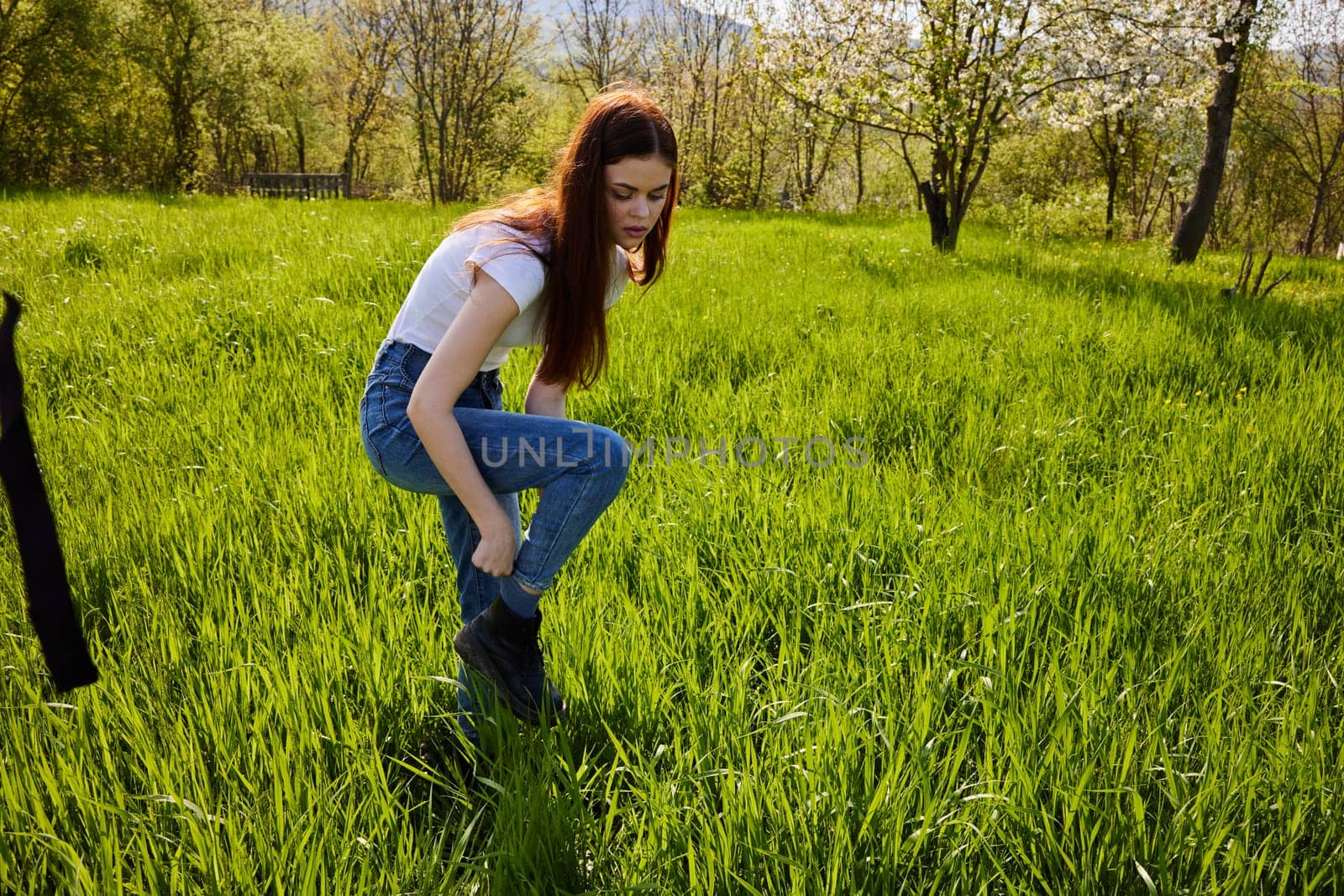 woman standing in tall grass adjusting her shoe. High quality photo