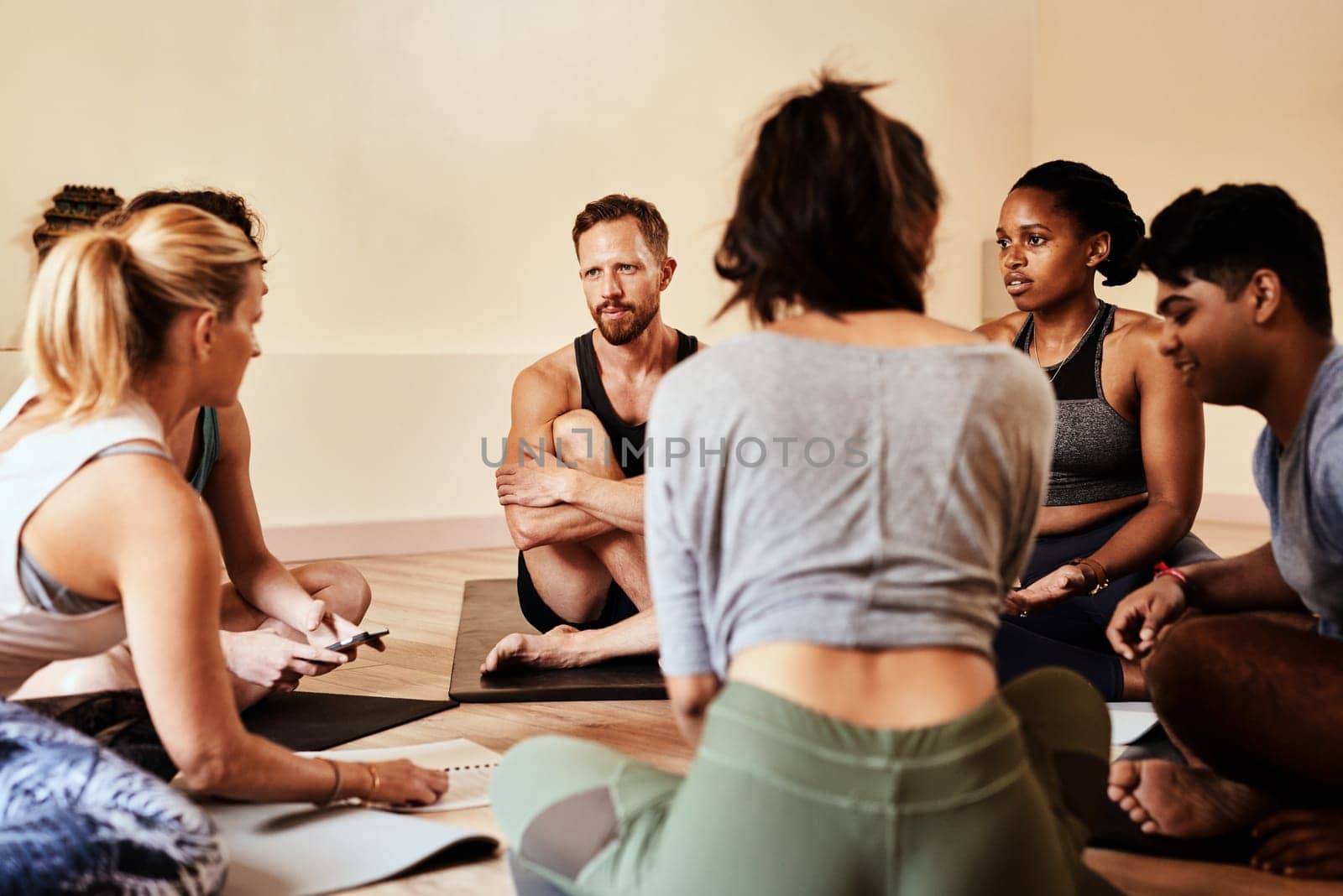 Yoga class, where your inner circle brings you inner peace. a group of young men and women chatting during a yoga class. by YuriArcurs