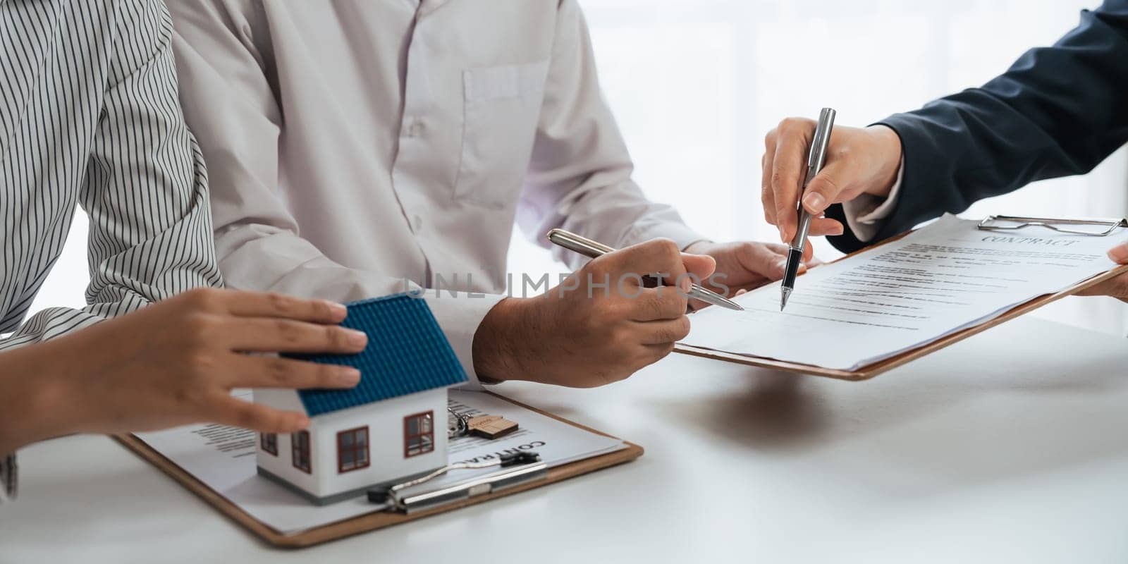 Happy couple signing a contract with real estate agent. renters tenants sign mortgage loan investment agreement or rental insurance contract meeting realtor lender landlord making real estate sale purchase deal.