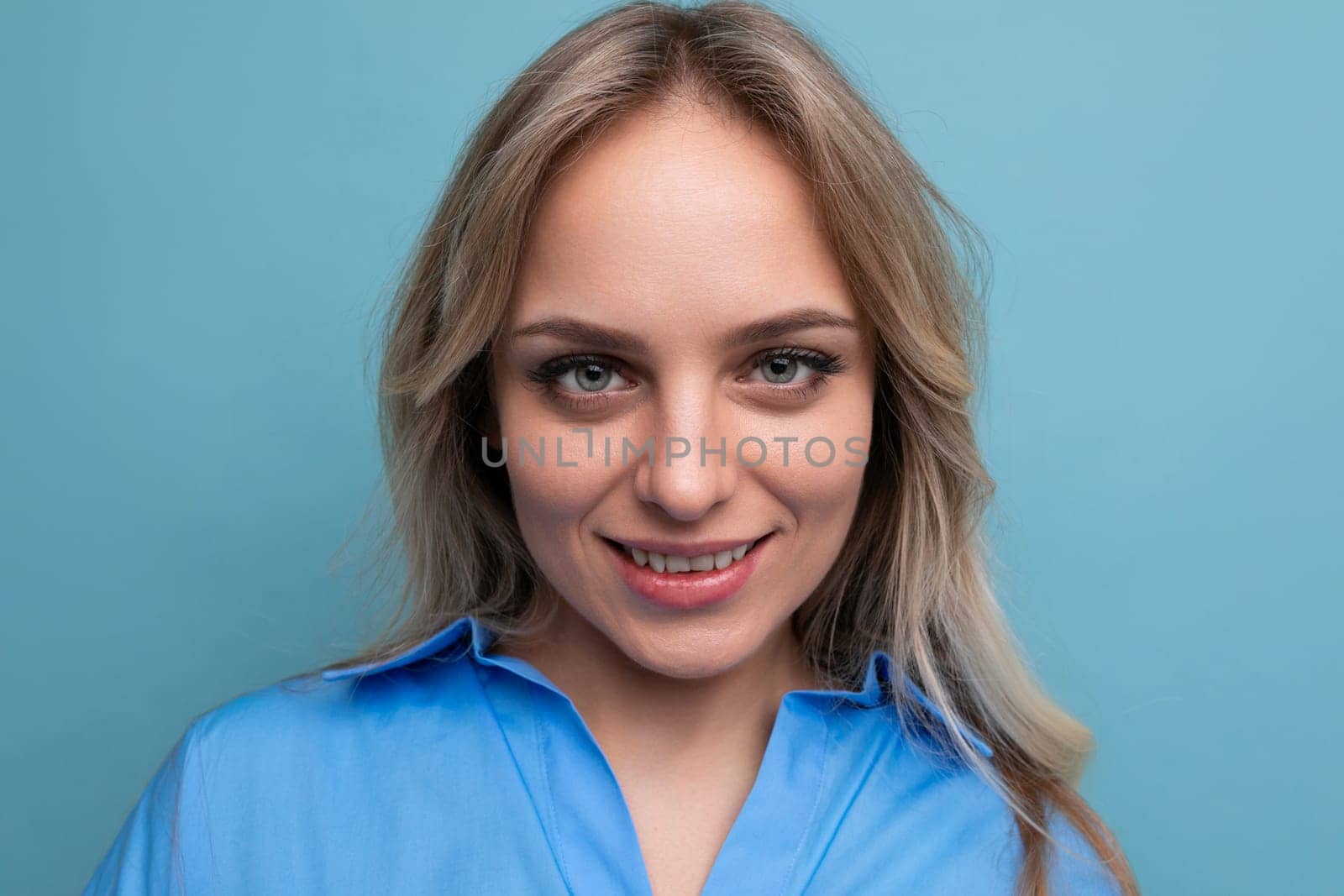 portrait of an adorable blonde young woman cutely closing her eyes on a blue background by TRMK