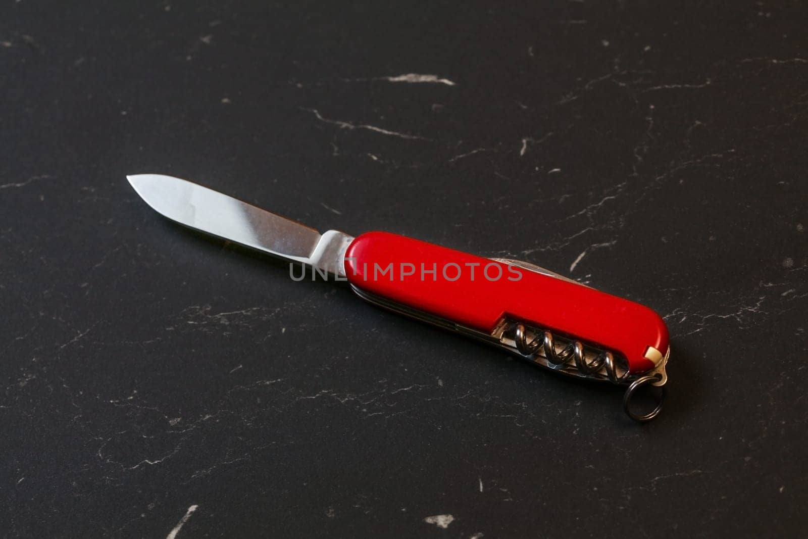 Red pocket knife on black table.