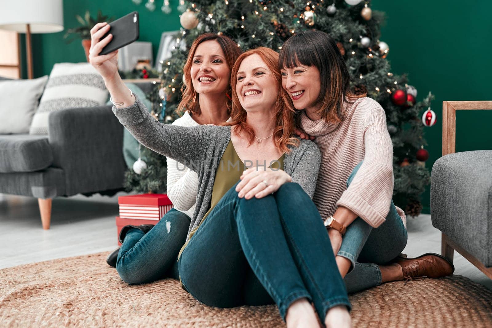 So that well remember forever. three attractive women taking Christmas selfies together at home. by YuriArcurs