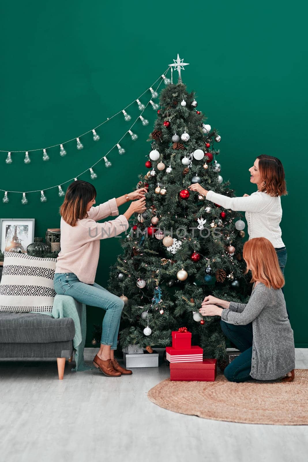 An art expression of festive excitement. three attractive women decorating a Christmas tree together at home
