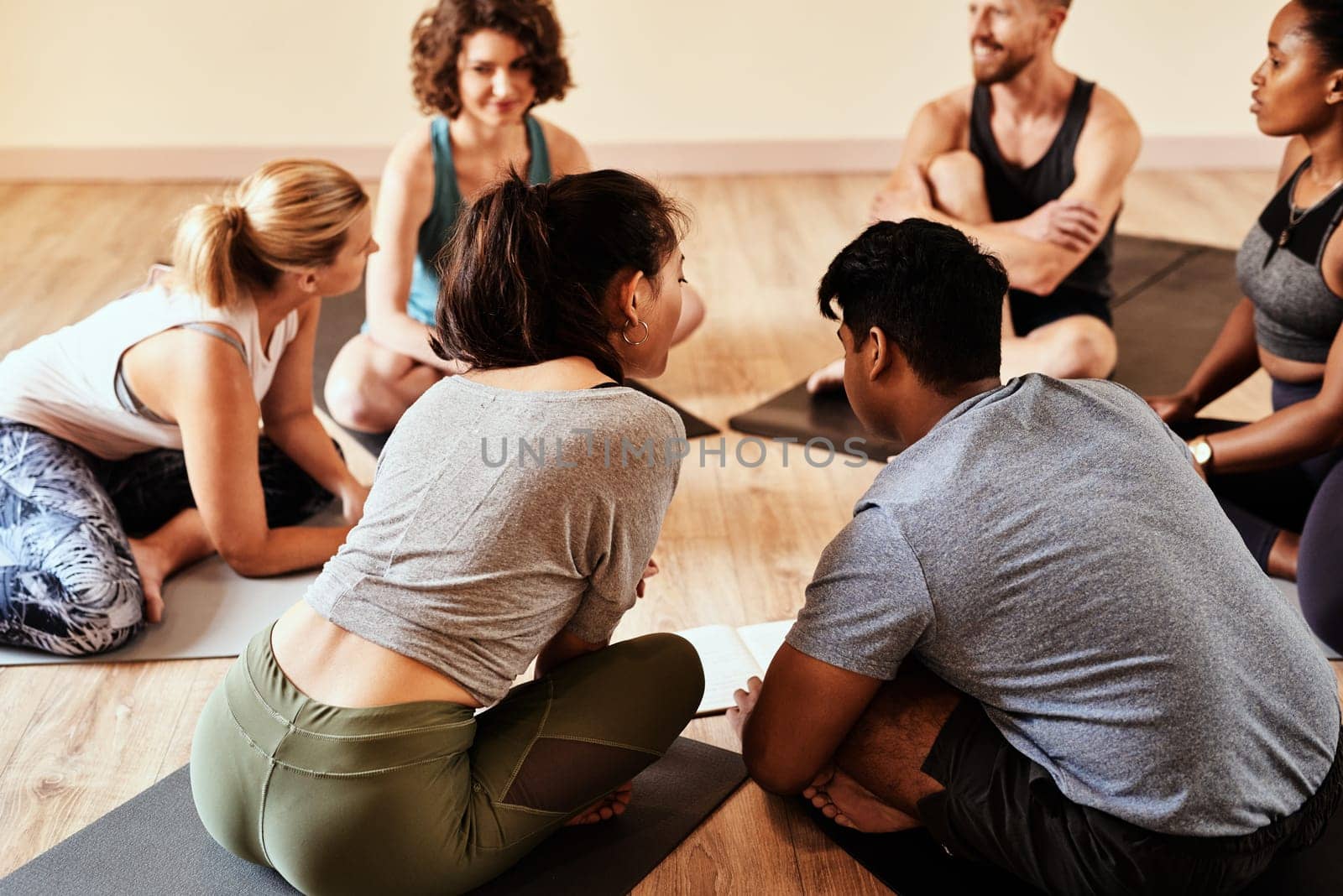 Theres place for everyone in this yoga class. a group of young men and women chatting during a yoga class