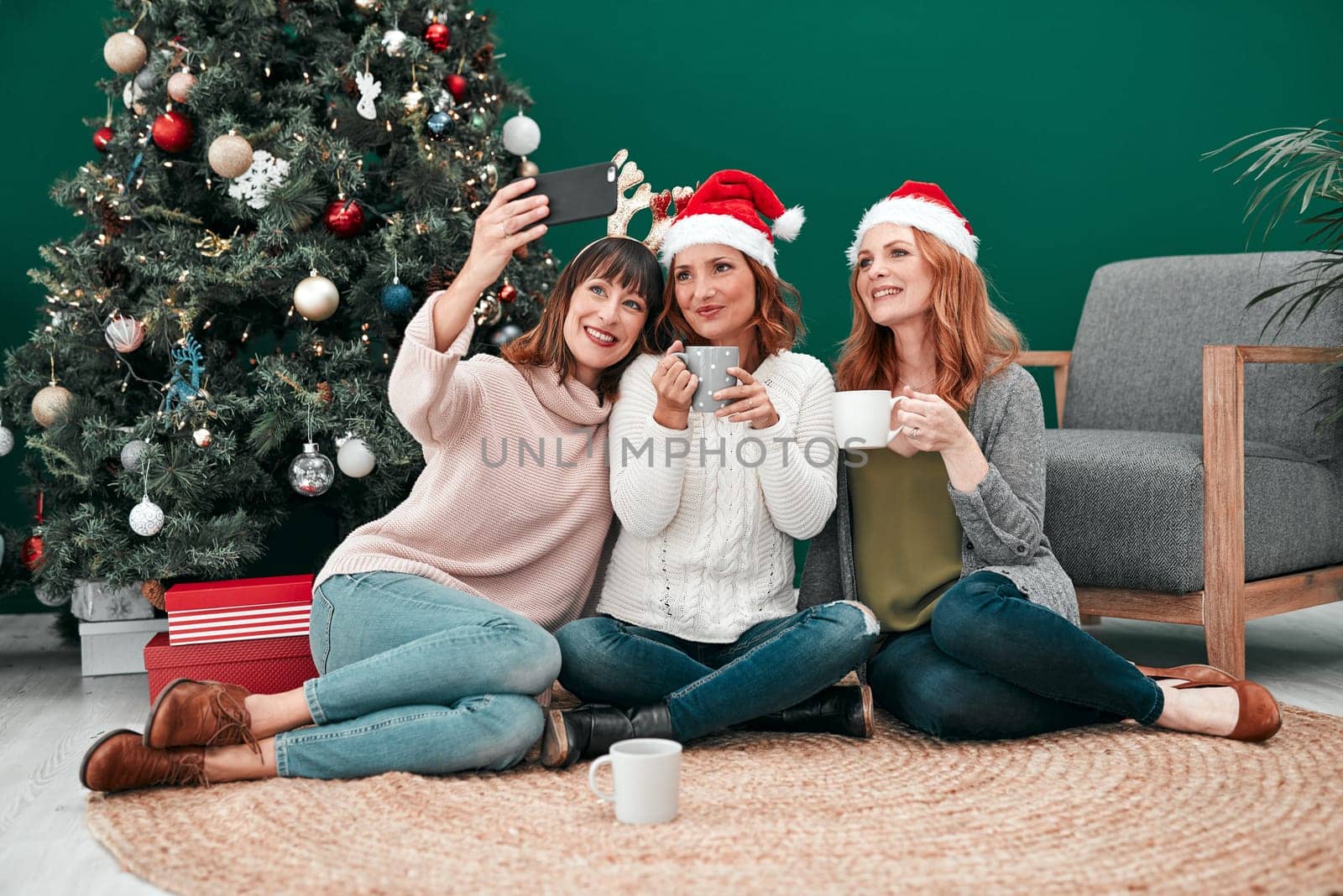 I cant wait to get this framed. three attractive women taking Christmas selfies together at home. by YuriArcurs