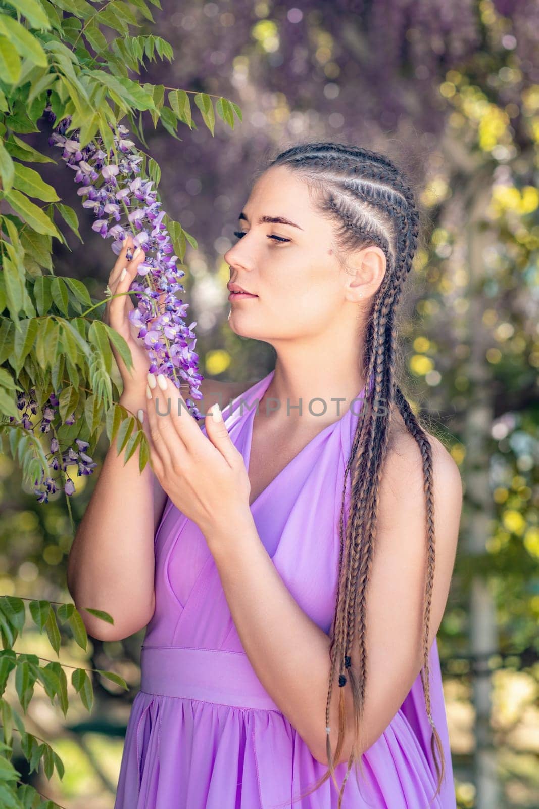 Woman wisteria lilac dress. Thoughtful happy mature woman in purple dress surrounded by chinese wisteria.