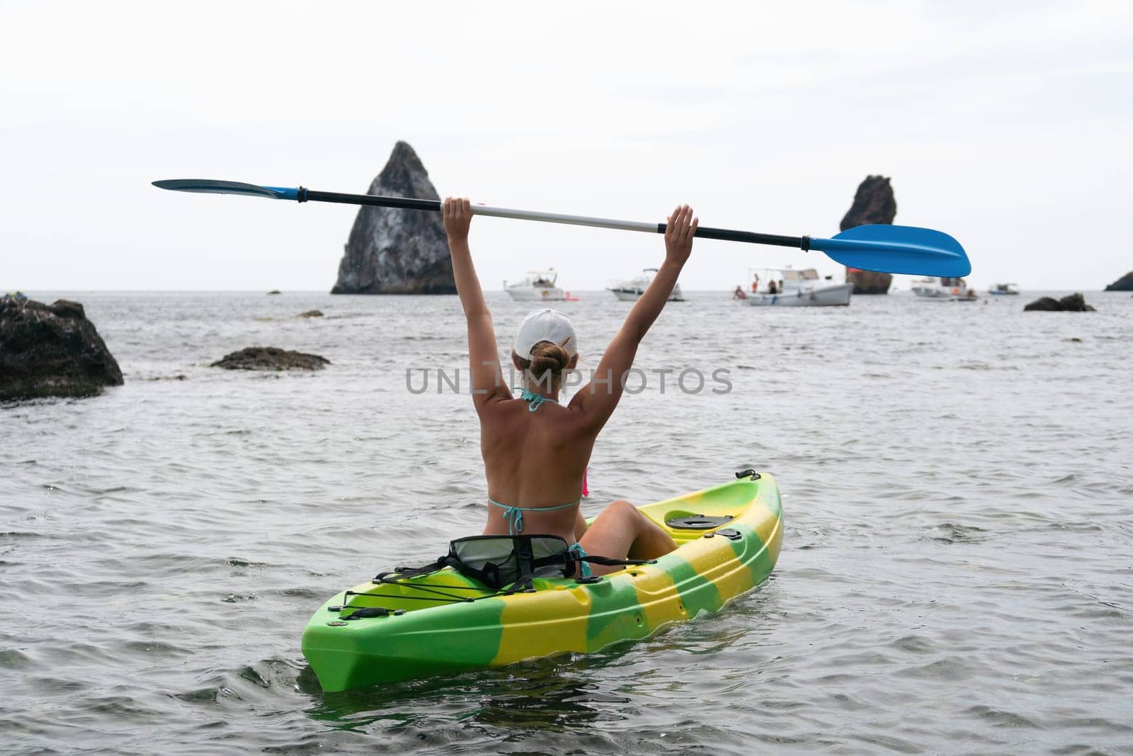 Woman kayak sea. Happy woman kayaks in sea, capturing outdoor memory with happy tourist taking photo. Volcanic mountains surround traveler on adventurous journey in kayak canoe. by panophotograph