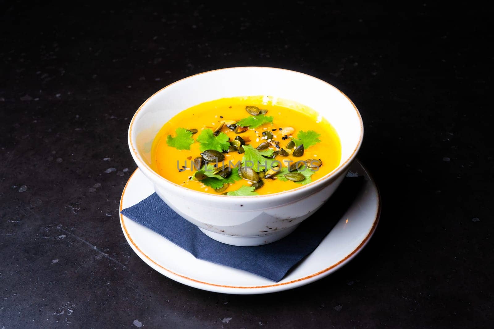 Pumpkin cream soup with parsley on a gray stone and wooden background. Top view, copy space