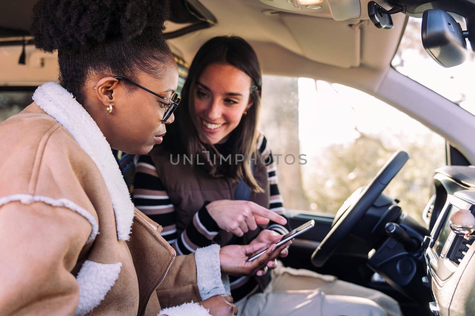 Two young women navigate camper trip on phone, concept of adventure and travel with best friend