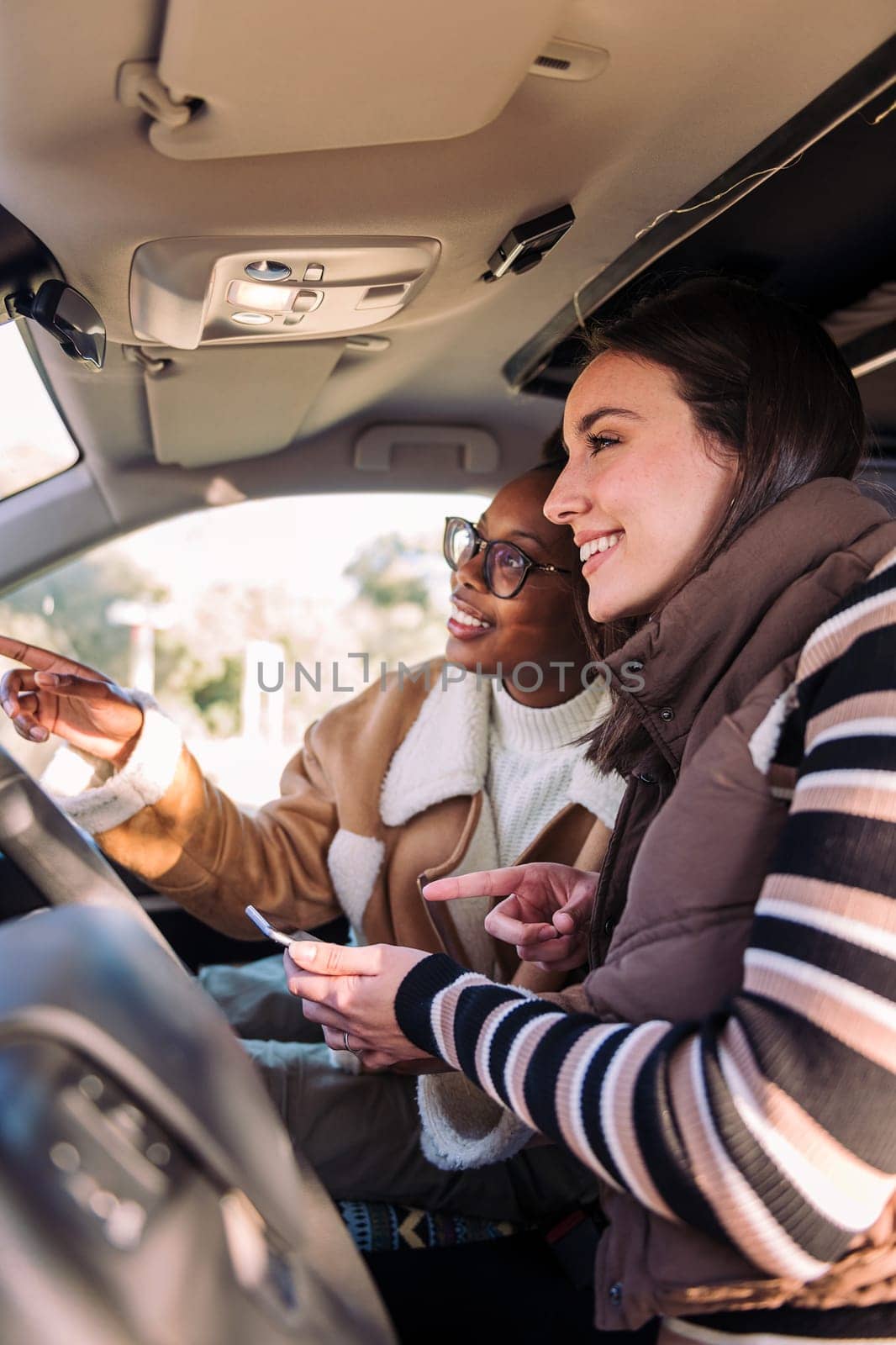 two young women in camper van planning road trip on the phone, concept of adventure and travel with best friend