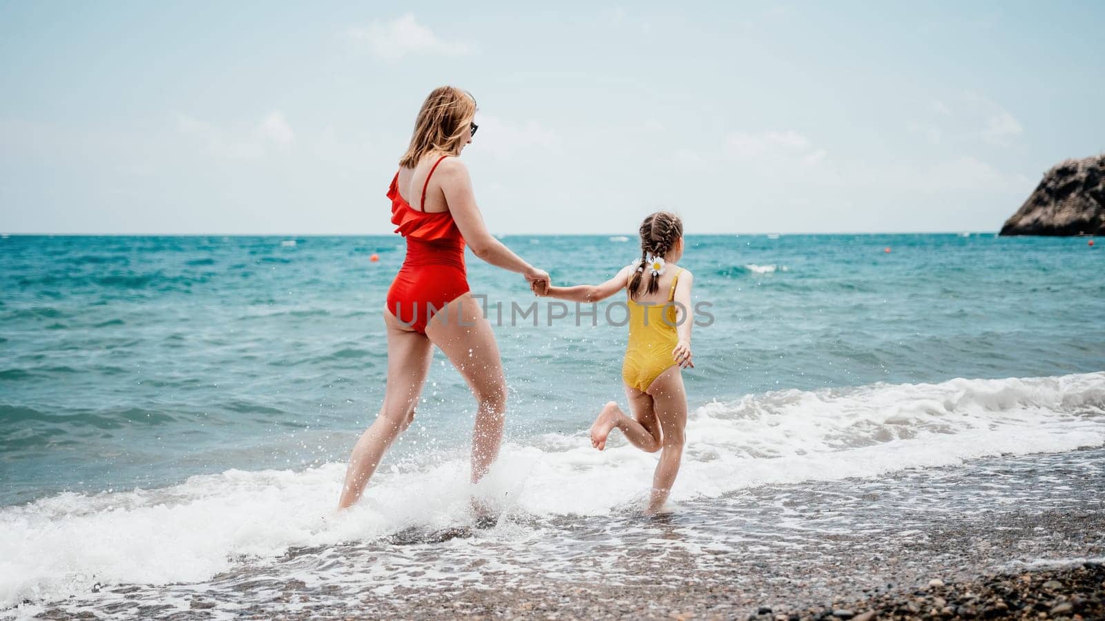 Happy loving family mother and daughter having fun together on the beach. Mum playing with her kid in holiday vacation next to the ocean - Family lifestyle and love concept.