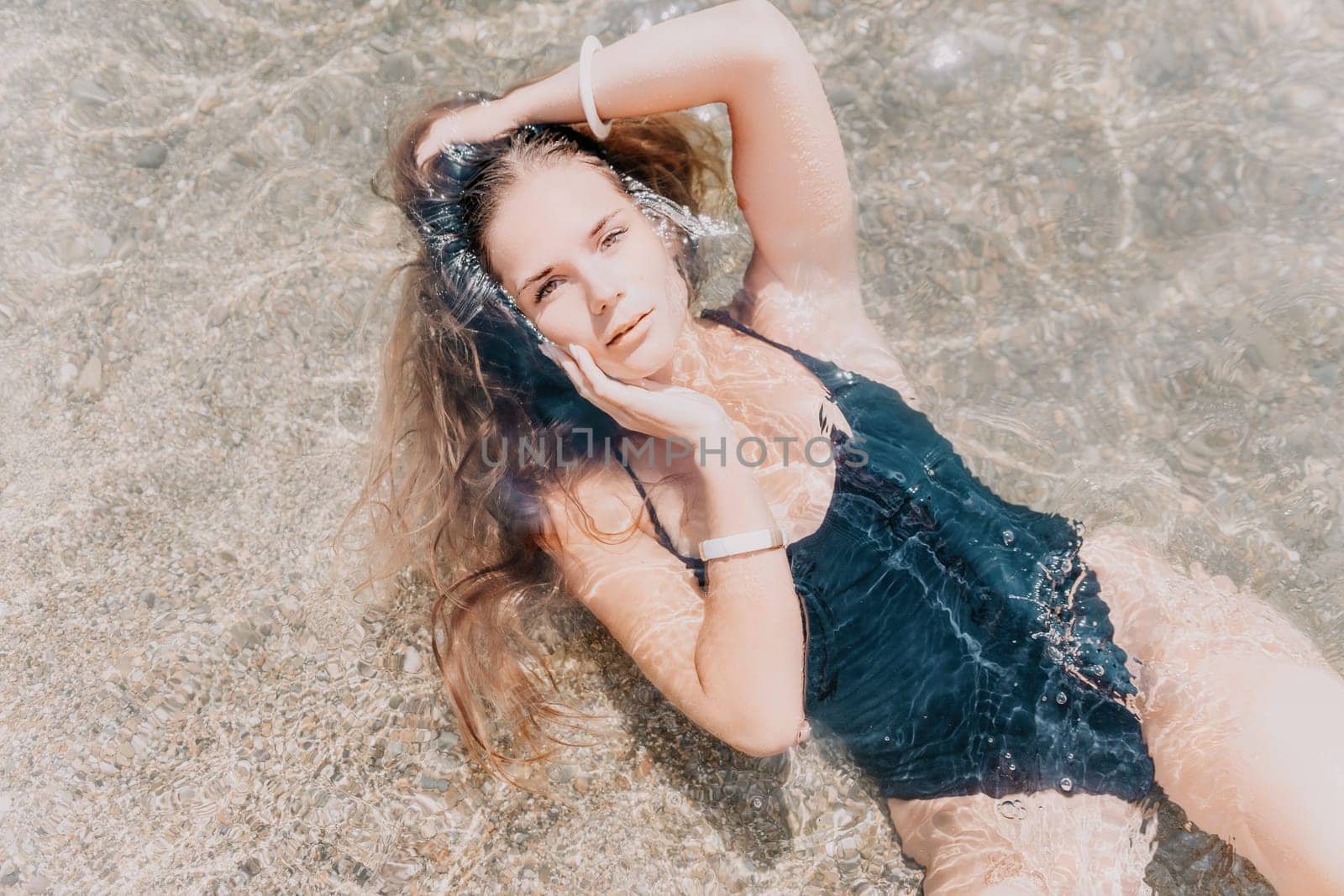 Woman travel sea. Young Happy woman in a long red dress posing on a beach near the sea on background of volcanic rocks, like in Iceland, sharing travel adventure journey