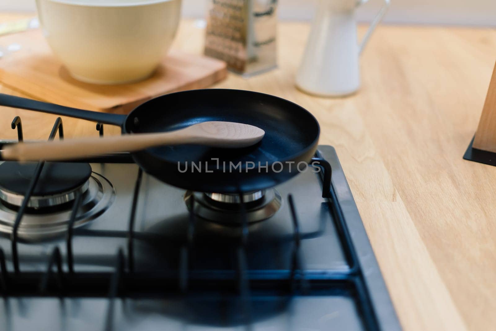 Spatula in skillet teflon coating pan on gas stove against spoon hanging in small kitchen by Zelenin