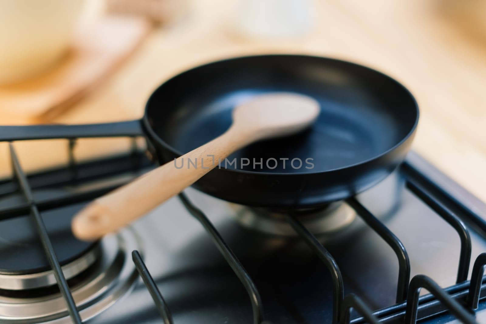 Spatula in skillet teflon coating pan on gas stove against spoon hanging in small kitchen by Zelenin