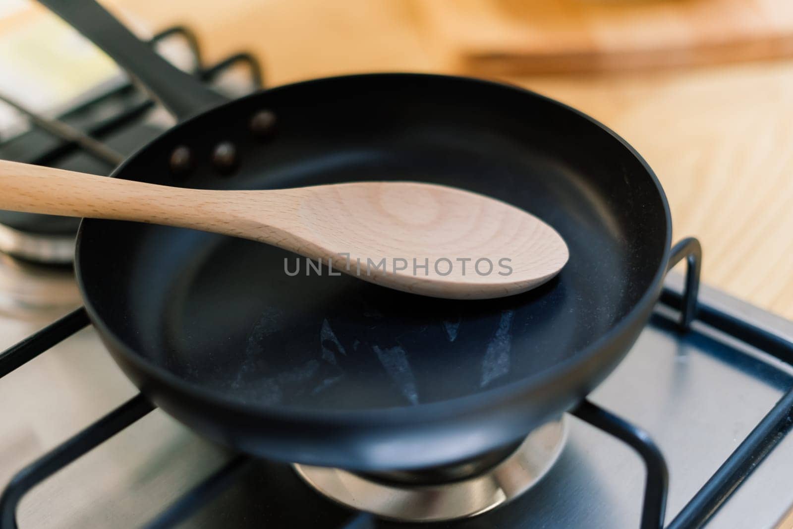 Spatula in skillet teflon coating pan on gas stove against spoon hanging in small kitchen by Zelenin