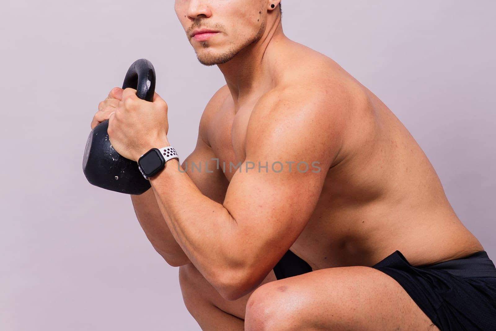 Strong young muscular focused fit man with a big muscles holding heavy kettlebells