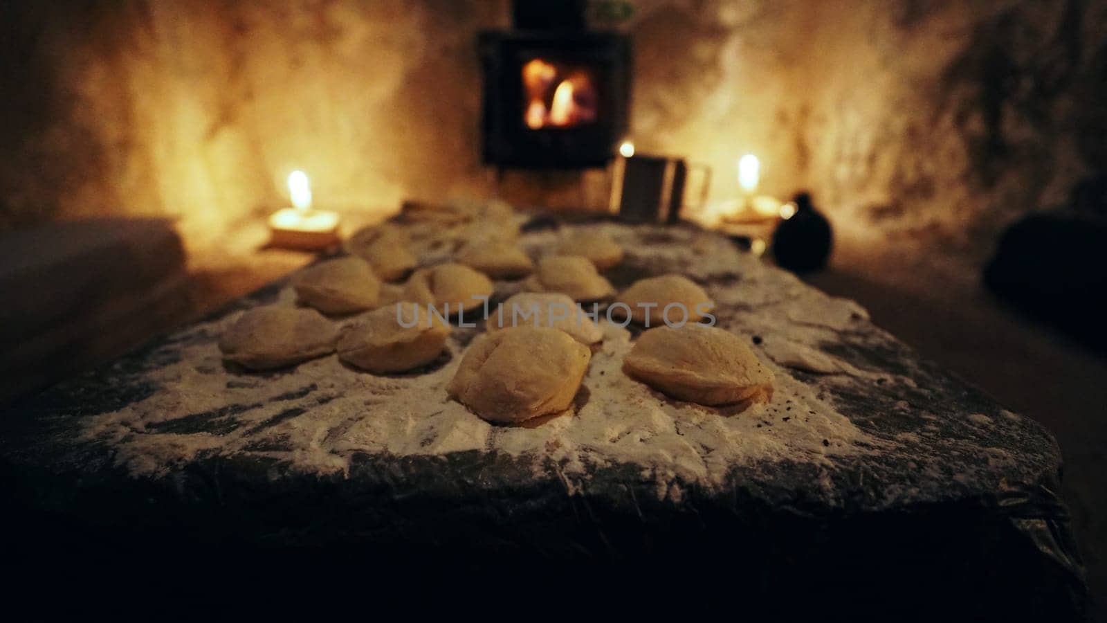 We made dumplings in field conditions. Cooking in an unusual place, in an old hut. There is a fire burning in the camp stove, candles next to the old walls. There are molded dumplings in flour