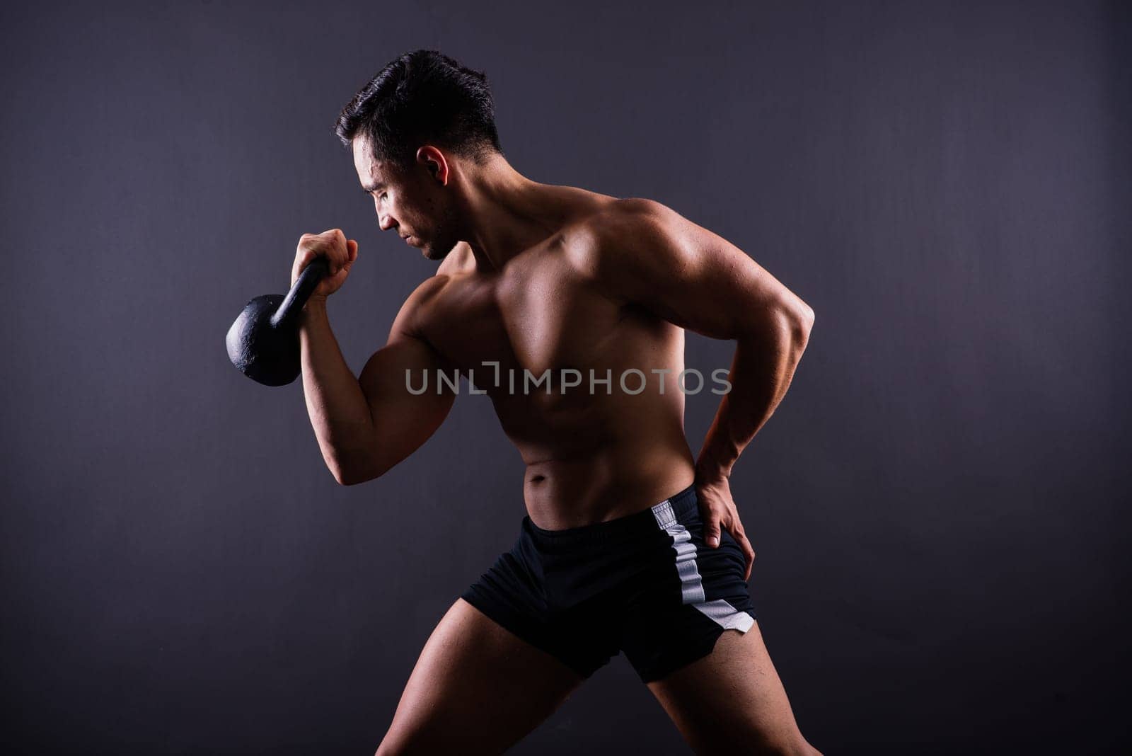 Strong young muscular focused fit man with a big muscles holding heavy kettlebells