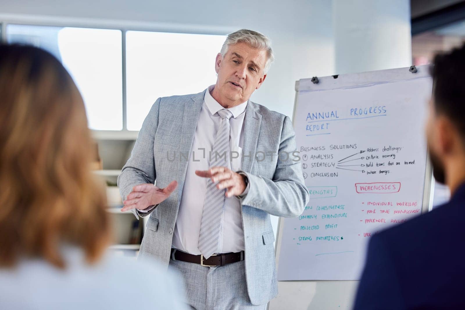 Senior businessman, presentation and meeting for staff training, coaching or planning by whiteboard at the office. Corporate CEO man presenter in team strategy or teaching employees in group seminar.
