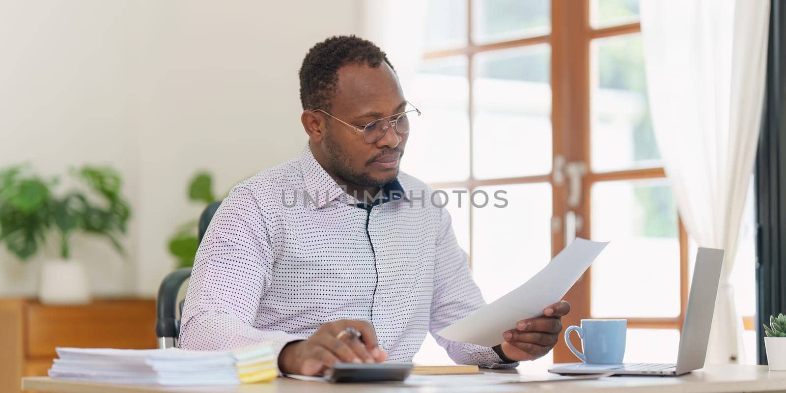 Smiling American African makes financial report and studies annual figures, analyzes profits. Accountant checks status of financial.