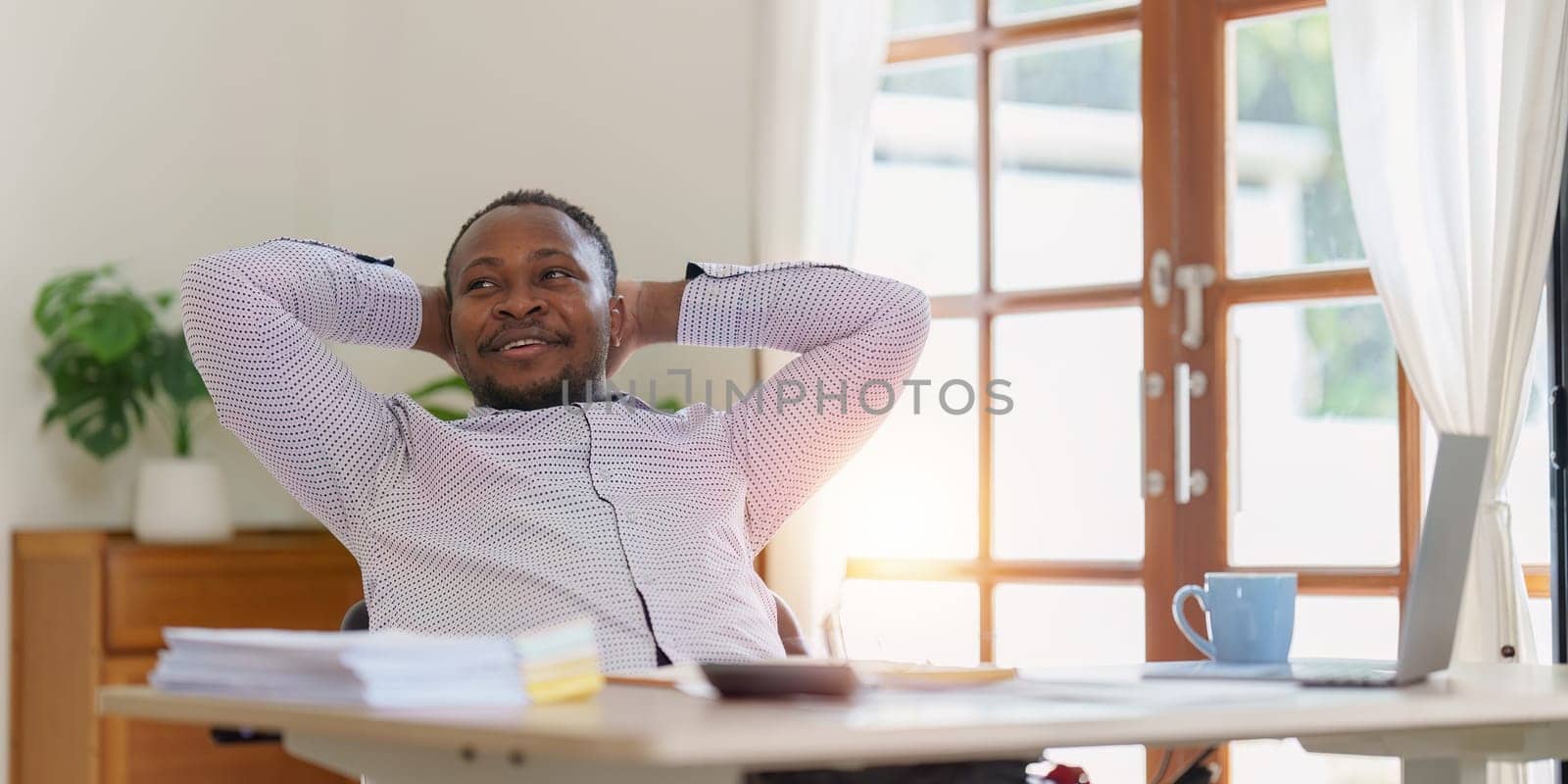 Smiling American African business person relaxing after analysis and research at home office.