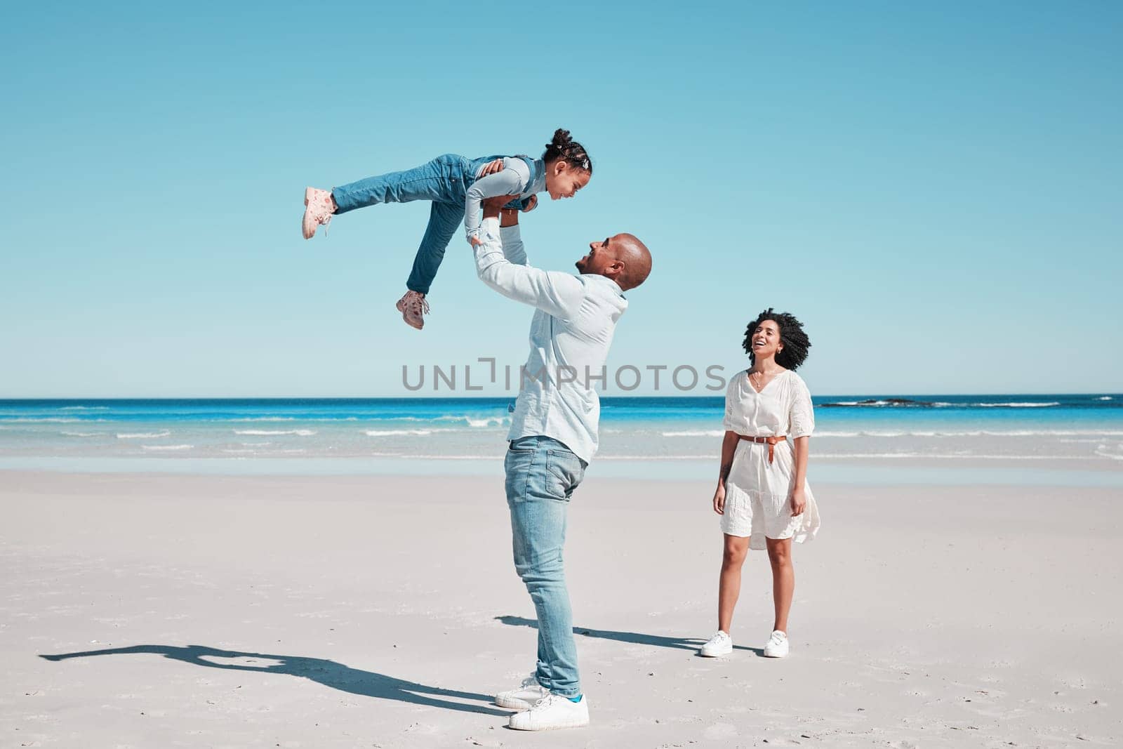 Playing, happy and child with parents at the beach for bonding, quality time and relaxation. Smile, family and playful girl kid with dad and mother at the ocean for holiday, happiness and summer.
