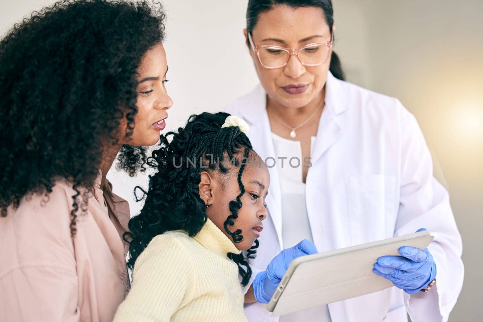 Tablet, healthcare and doctor with a mother and child in discussion on test results in the hospital. Professional, communication and female medical worker on a mobile device with the mom and kid