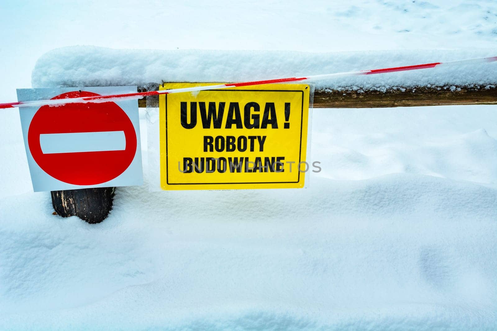 No entry sign on the fence and yellow in Polish, Attention Works, winter snowy day
