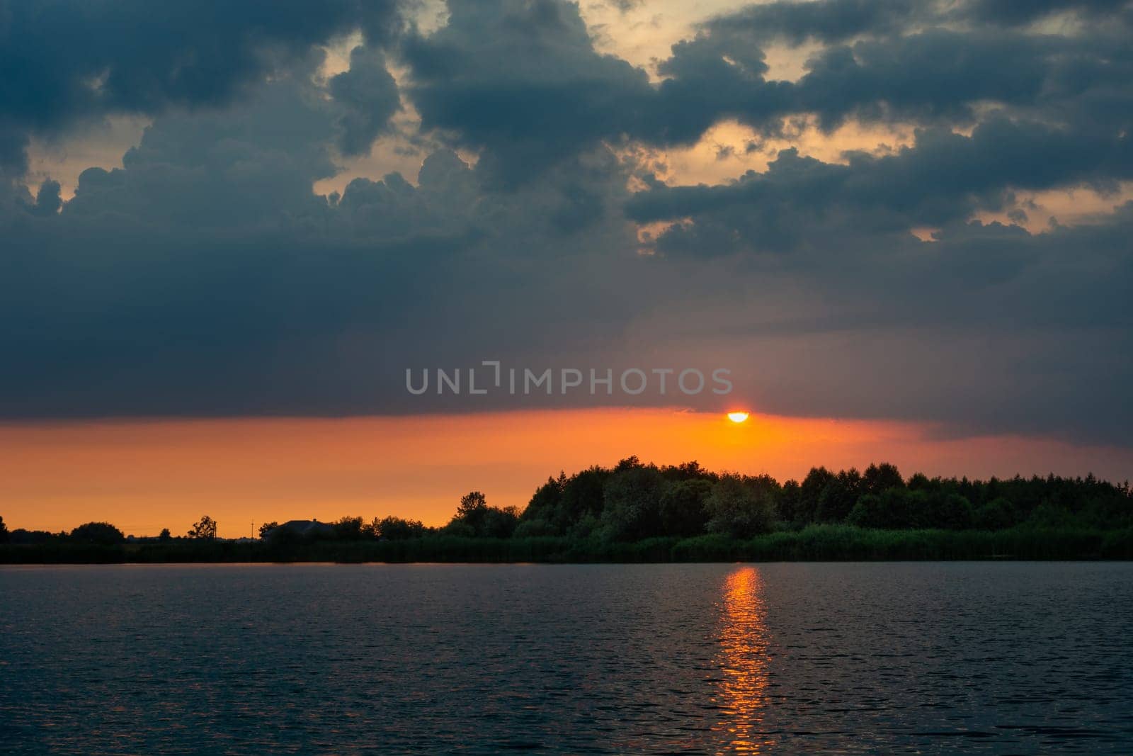 Sunset with dark clouds over the calm lake