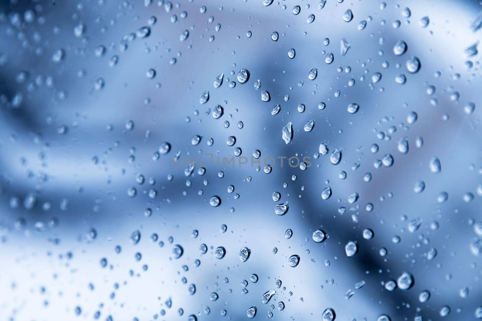 natural water drops on the window glass. blue background with rain on the window, close-up by yanik88