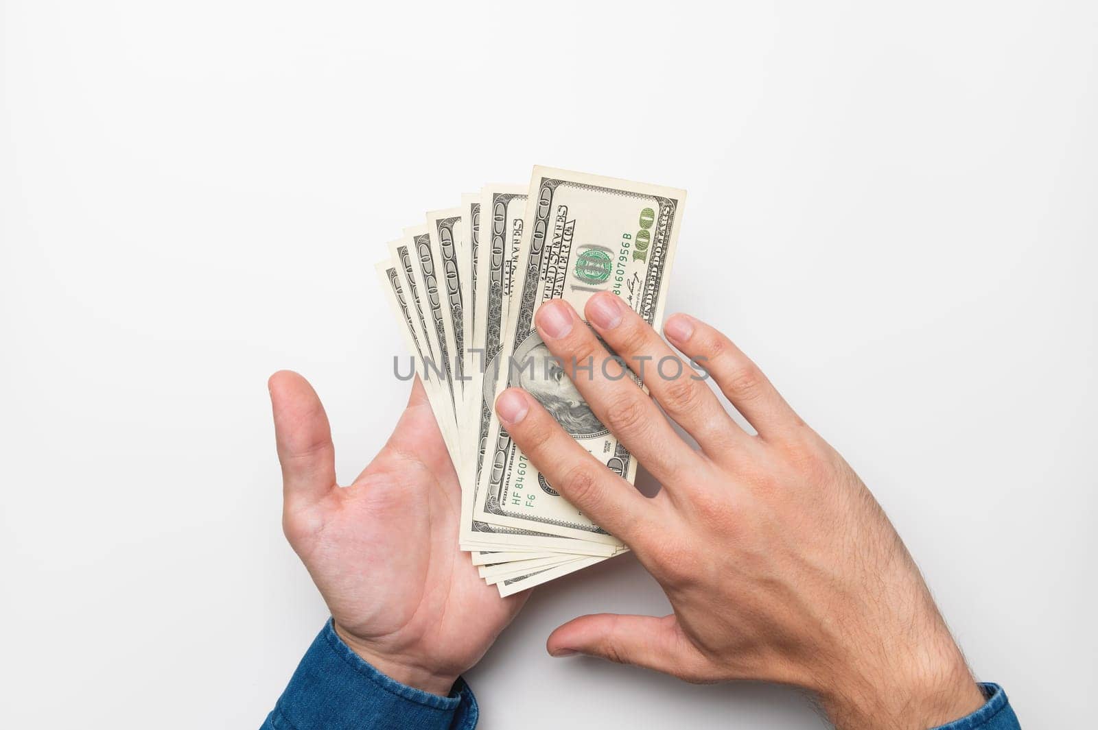 human hand with money on a white background. male hands in a shirt hold out and spend one hundred dollar bills.