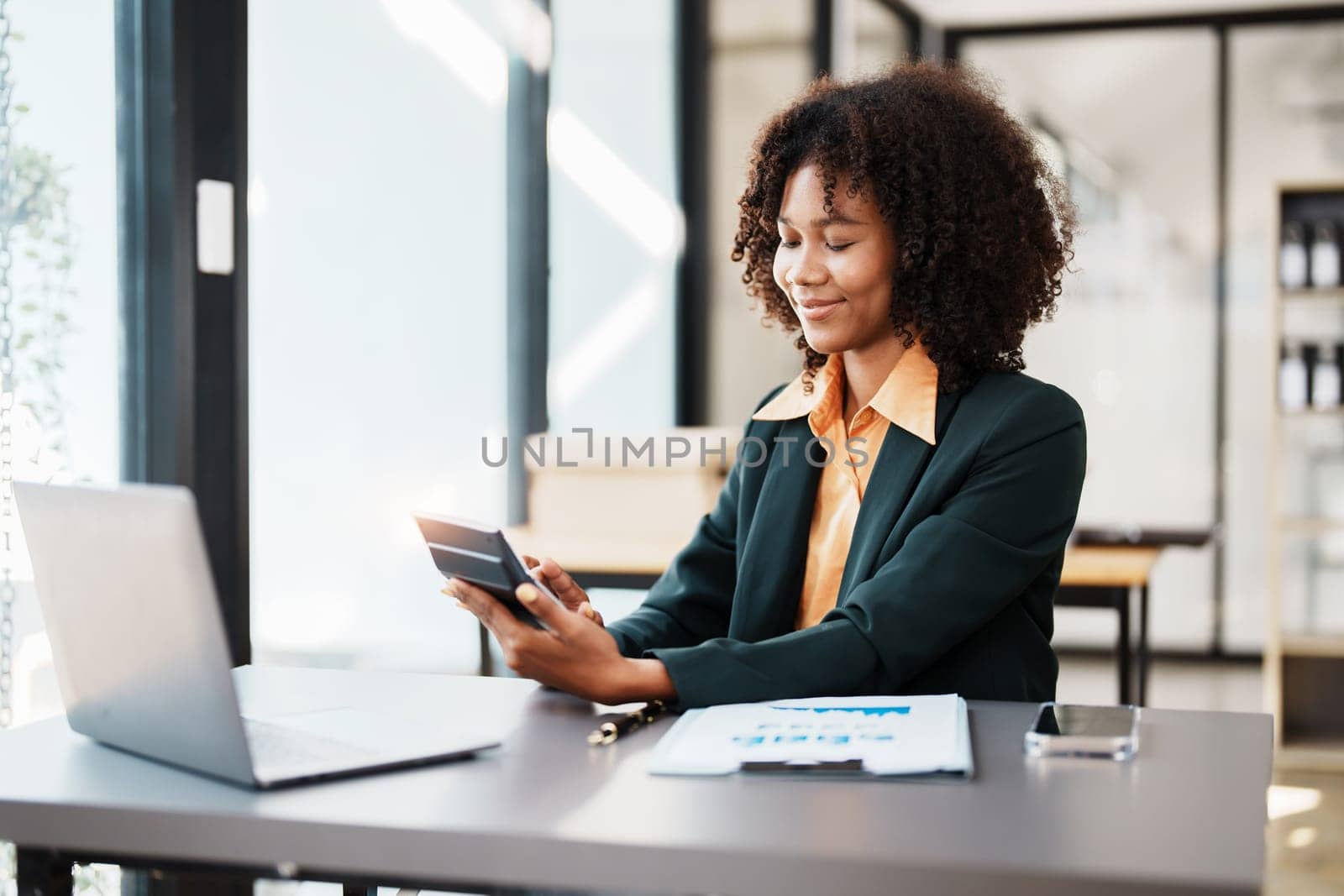 Beautiful young teen American African using calculator for calculating and computer laptop with planning working on financial document, tax, exchange, accounting and Financial advisor.