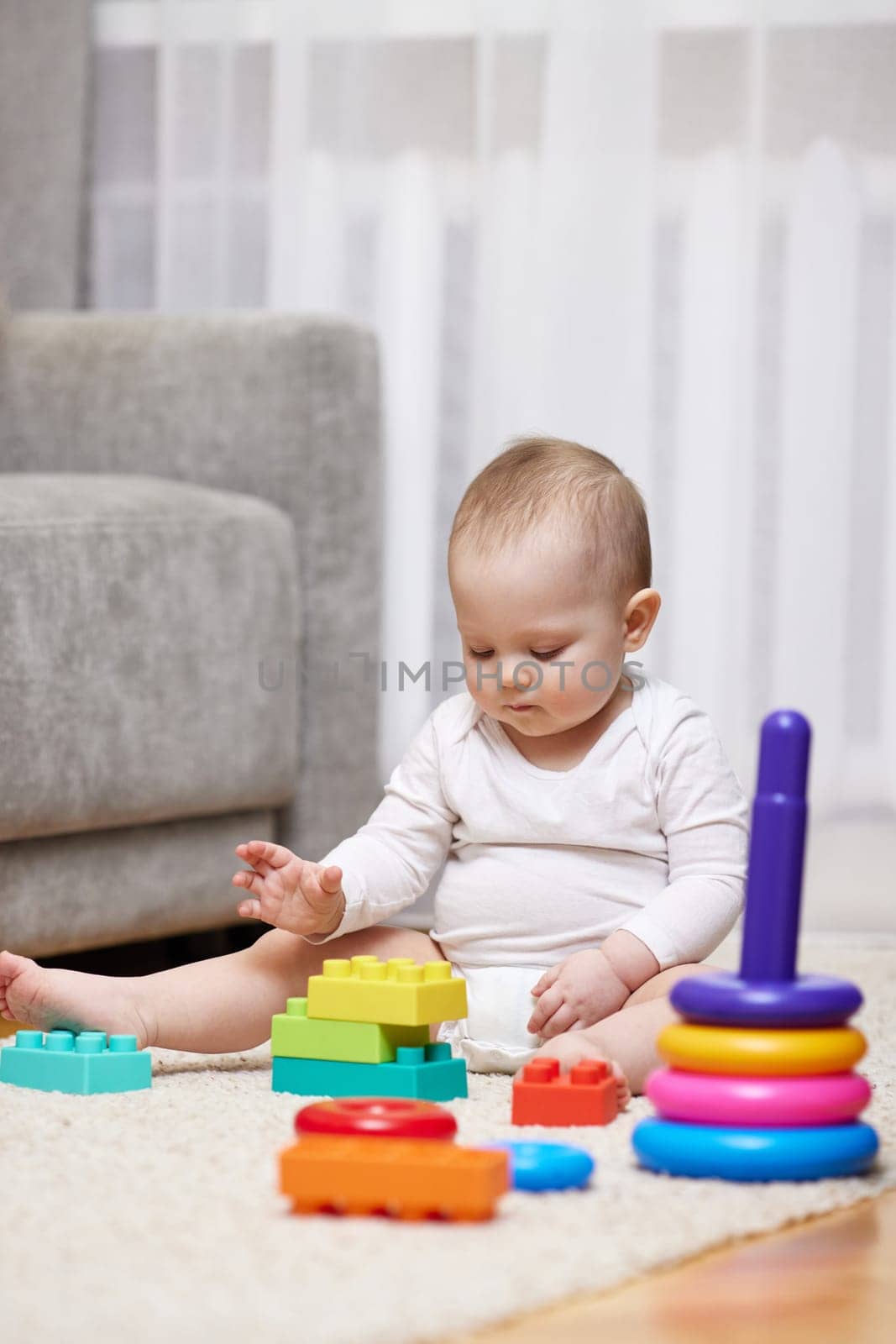cute baby girl playing with toys on carpet at home