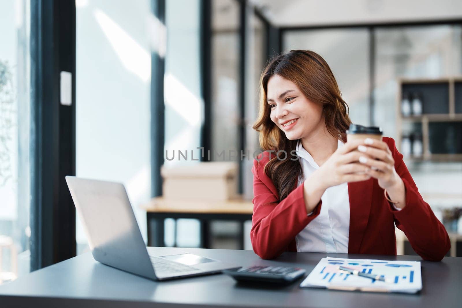 Beautiful young teen asian businesswomen using computer laptop and drink coffee with in smile winner is gesture, Happy to be successful celebrating achievement success by Manastrong