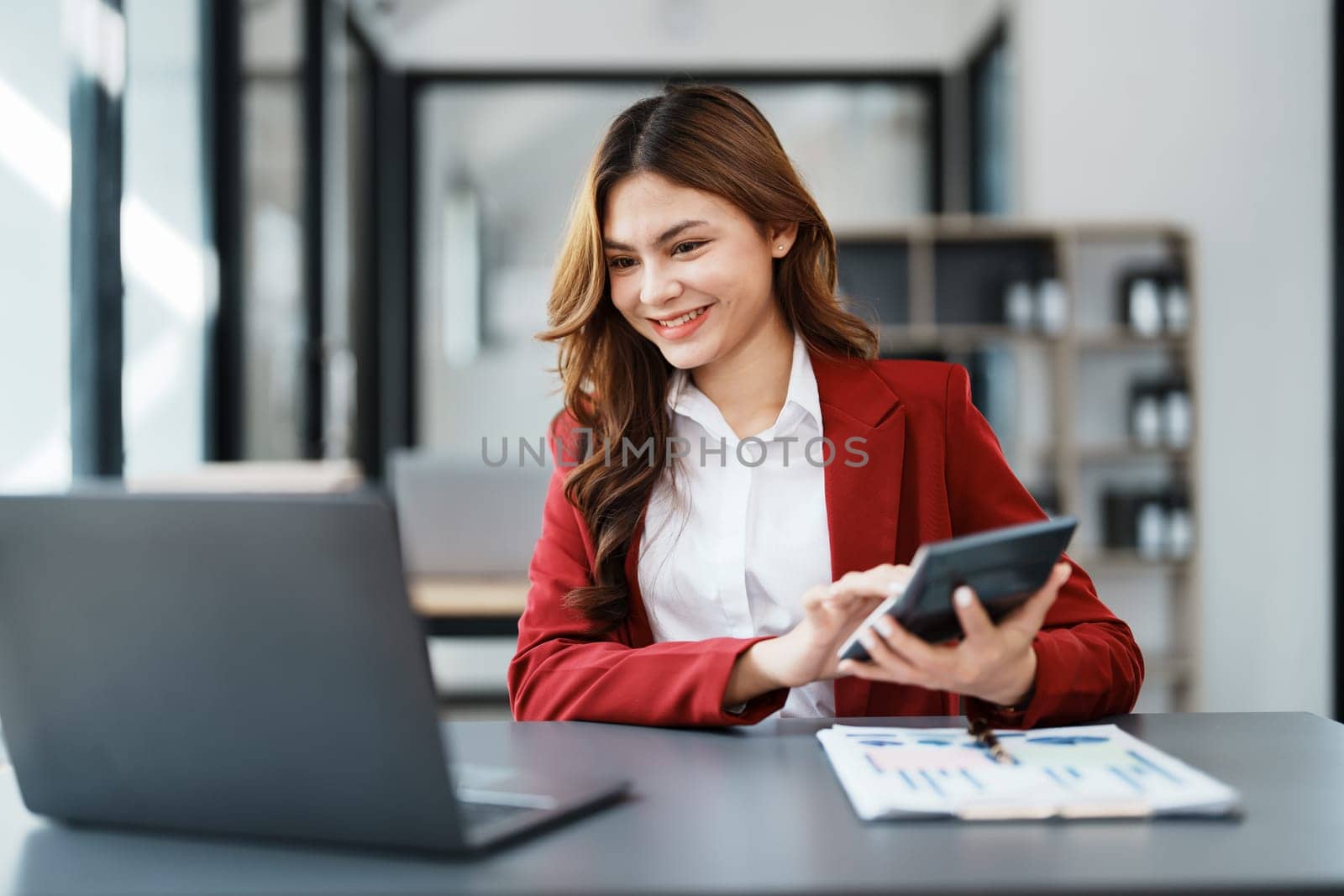 Beautiful young teen asian businesswoman using computer laptop and calculator for calculate with planning working on financial document, tax, exchange, accounting and Financial advisor by Manastrong