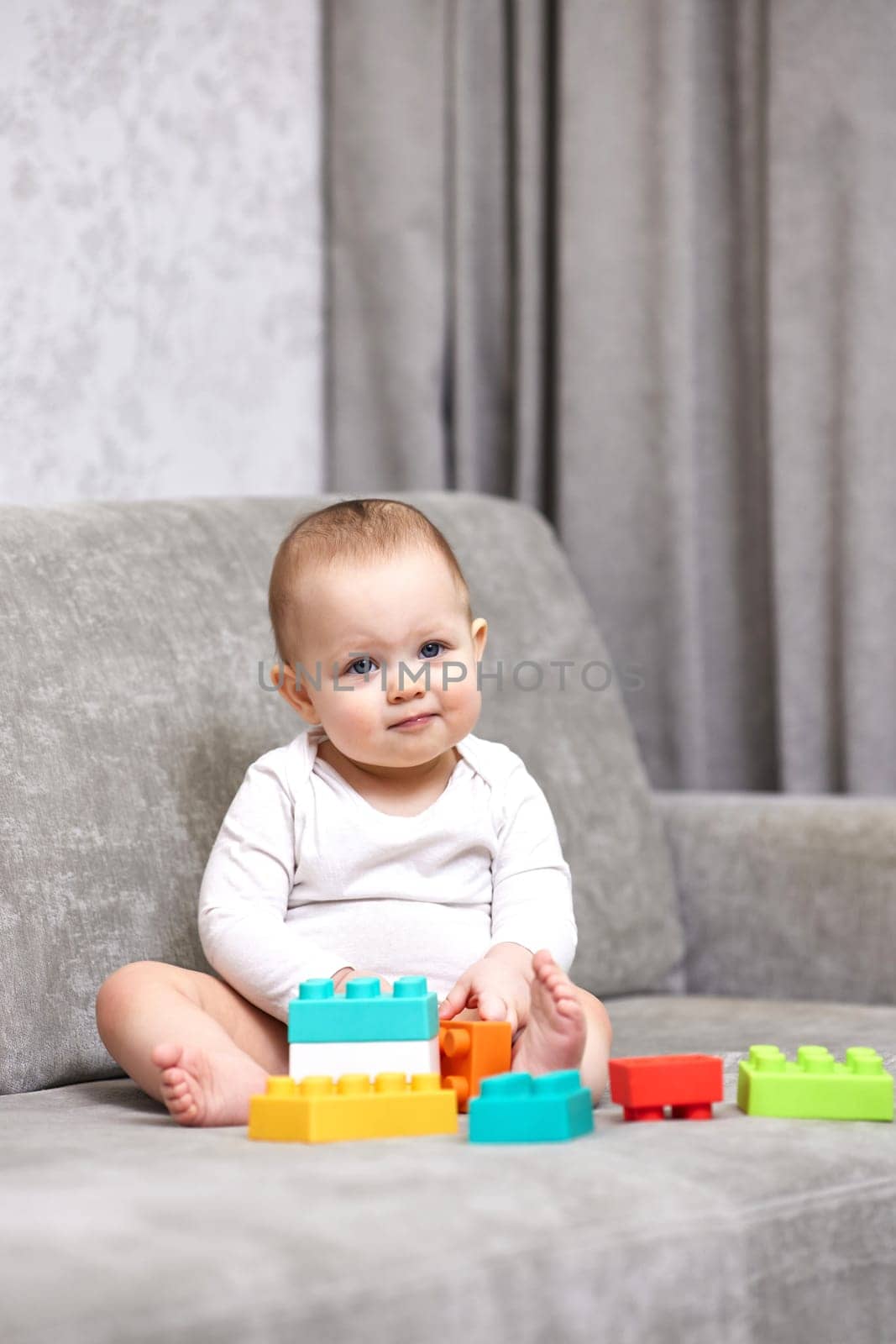 cute baby girl playing with colorful toy blocks at home