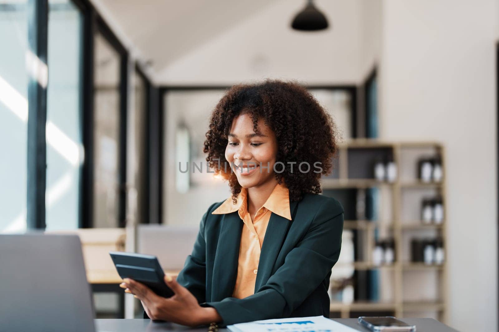 Beautiful young teen American African using calculator for calculating and computer laptop with planning working on financial document, tax, exchange, accounting and Financial advisor.