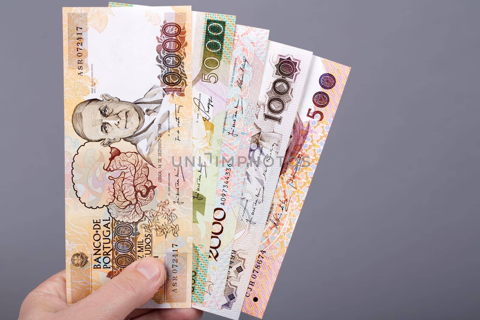 Portuguese money - Escudo  in the hand on a gray background