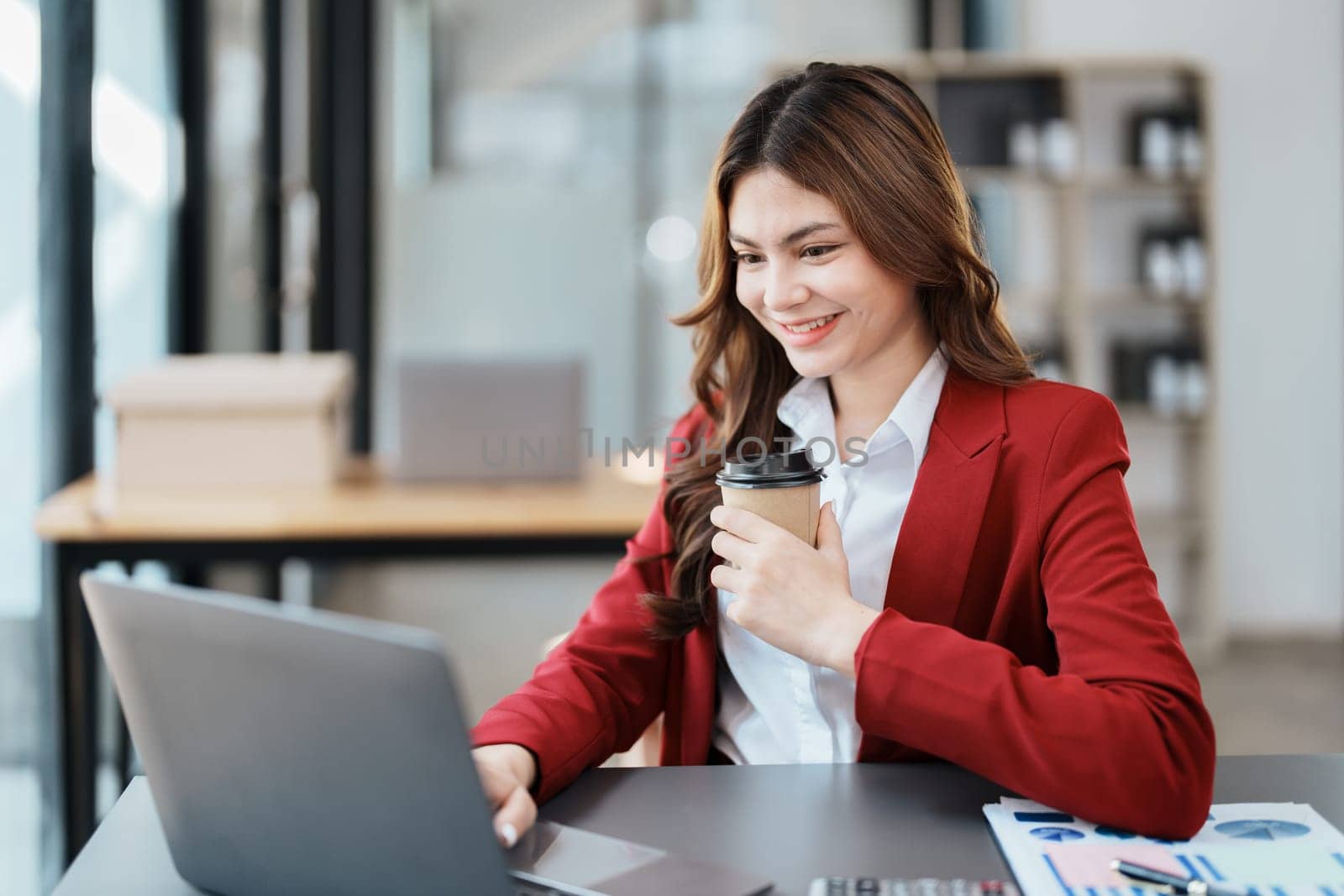 Beautiful young teen asian businesswomen using computer laptop and drink coffee with in smile winner is gesture, Happy to be successful celebrating achievement success by Manastrong