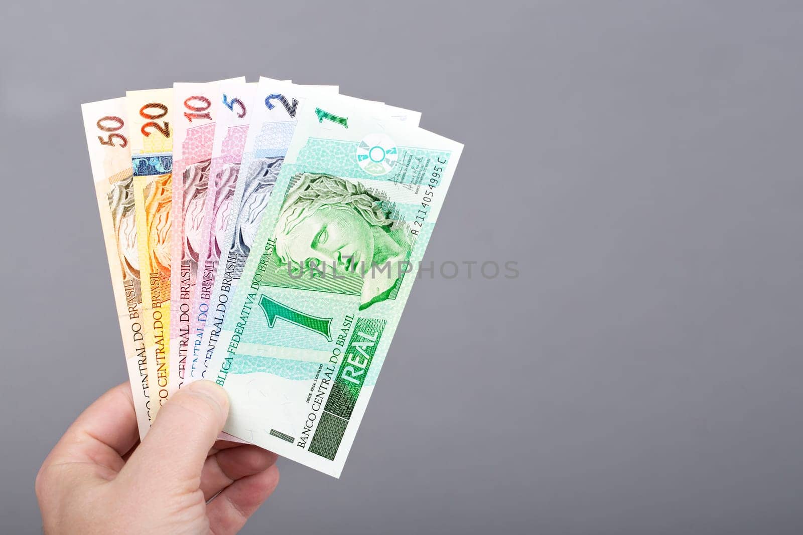 Old Brazilian money in the hand on a gray background by johan10