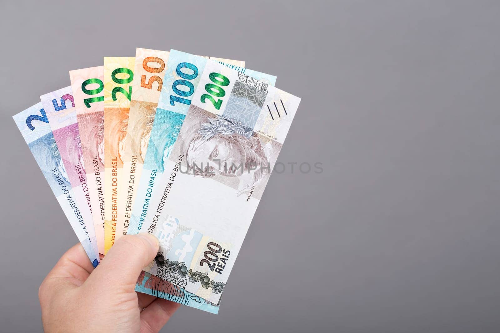 Brazilian money in the hand on a gray background	 by johan10