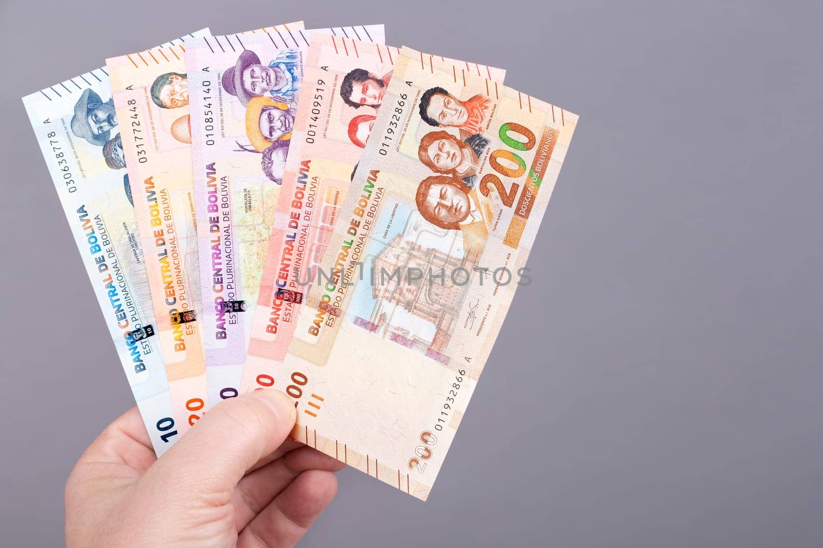 Bolivian money - Bolivianos in the hand on a gray background	
