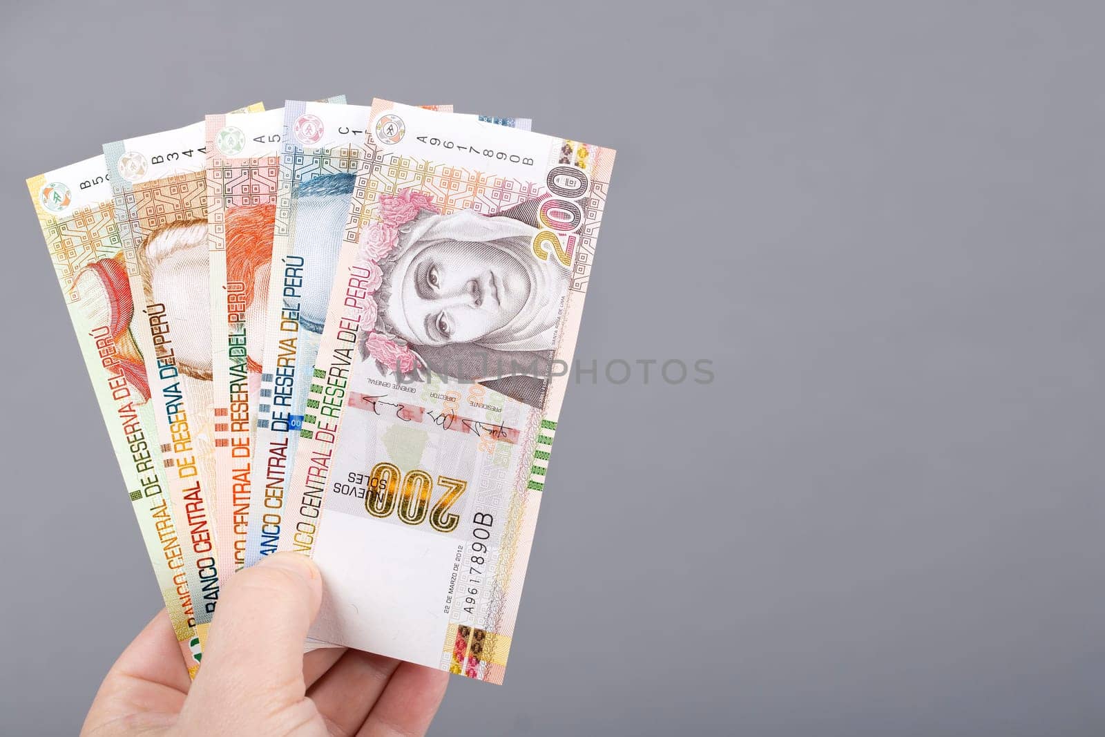 Peruvian money - Soles in the hand on a gray background