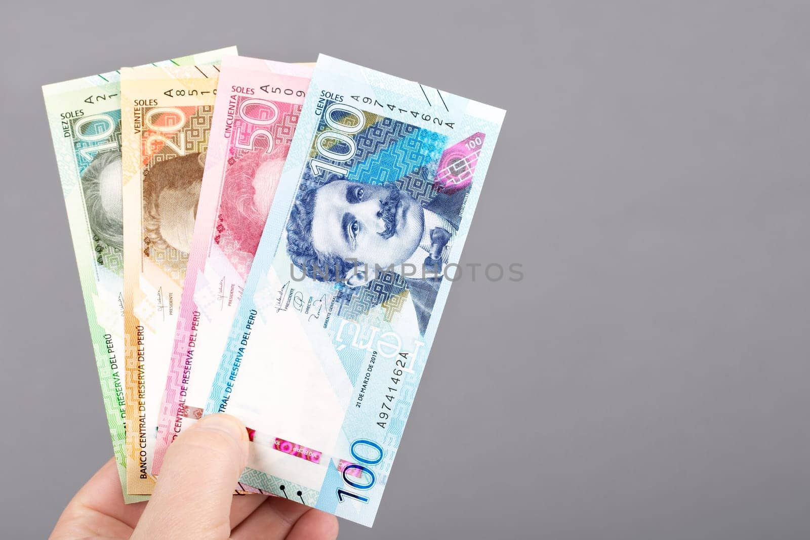 Peruvian money - Soles in the hand on a gray background	