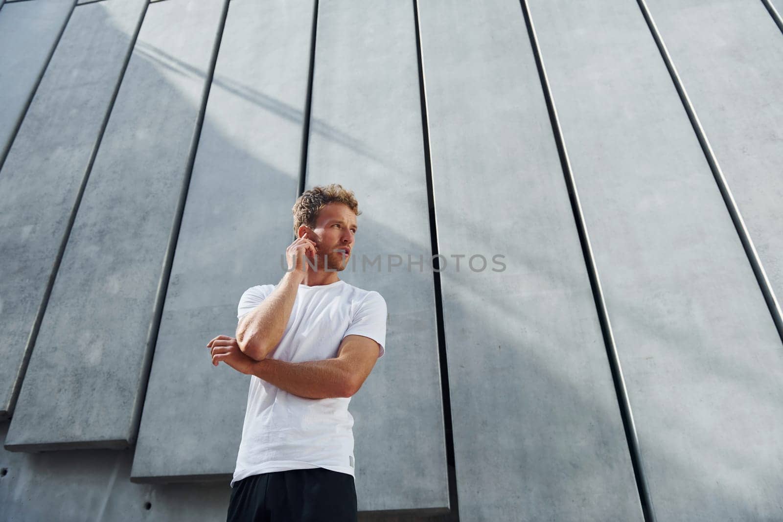 Against building exterior. Young man in sportive clothes have workout outdoors at daytime.