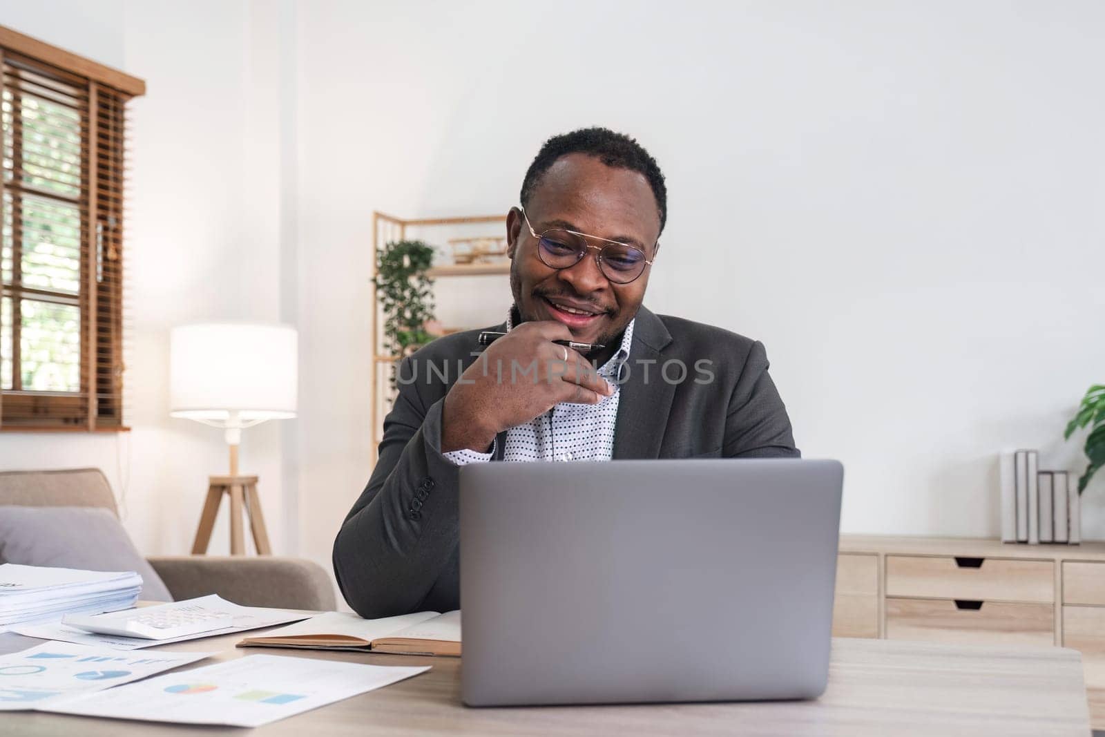 African American businessman using his laptop computer while working remotely from home. Online working or learning concept by nateemee