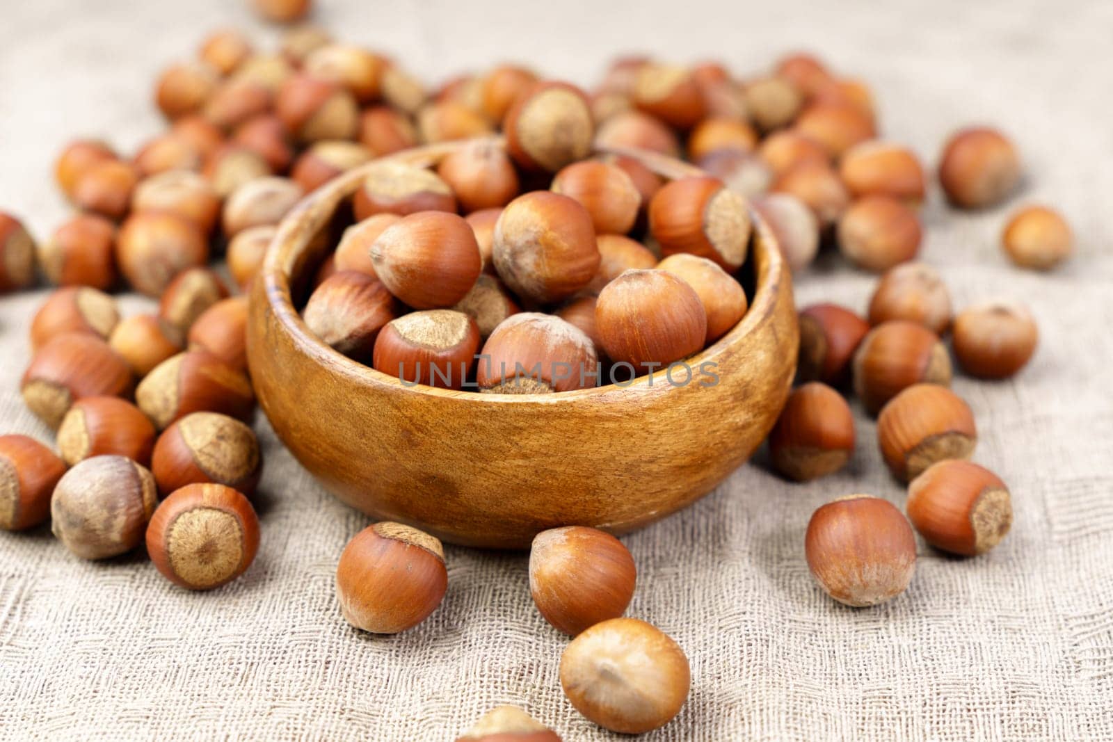 Hazelnuts in wooden bowl on a linen napkin background. Organic hazelnut.
