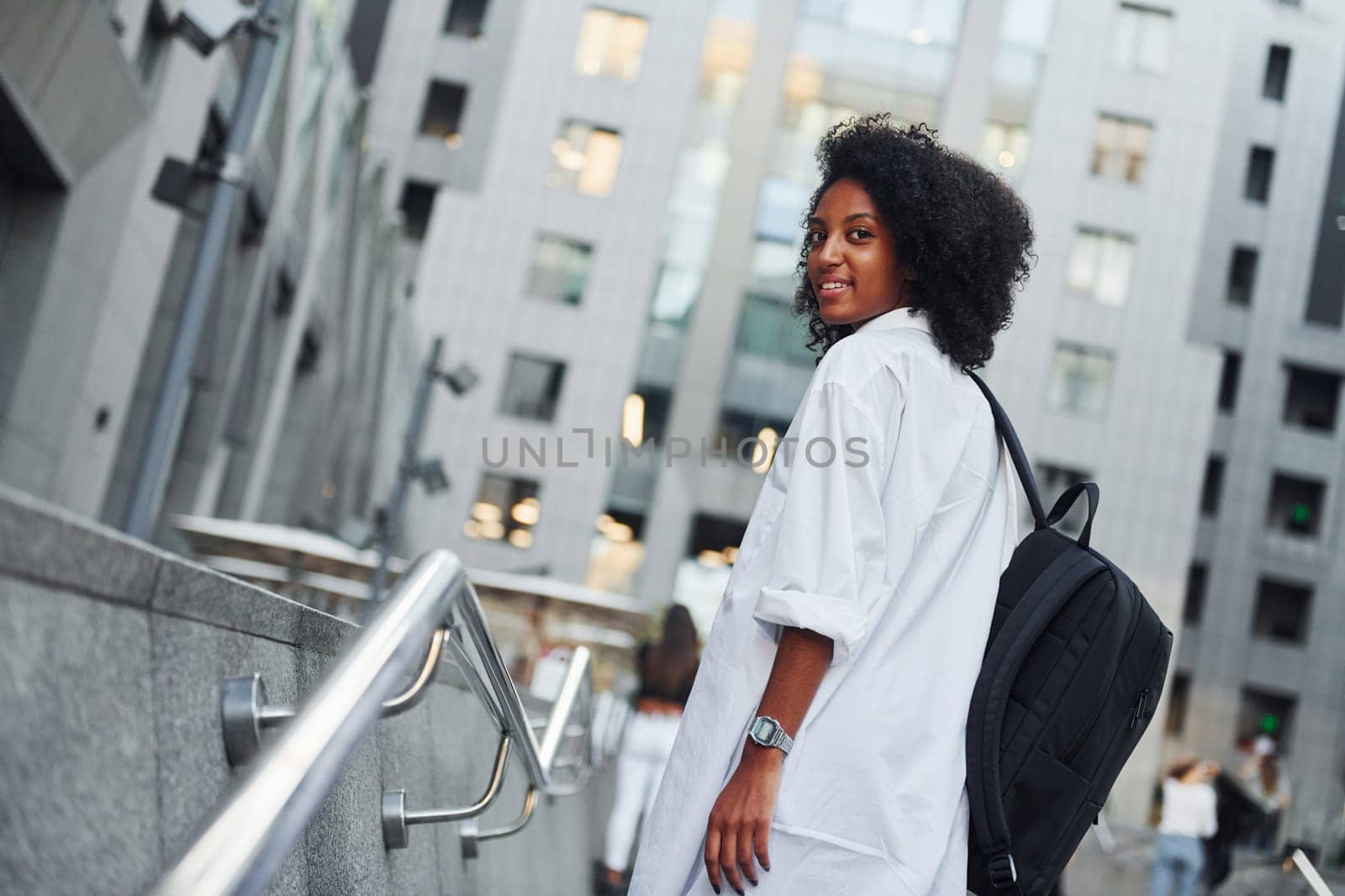African american woman in good clothes is outdoors in the city at daytime.