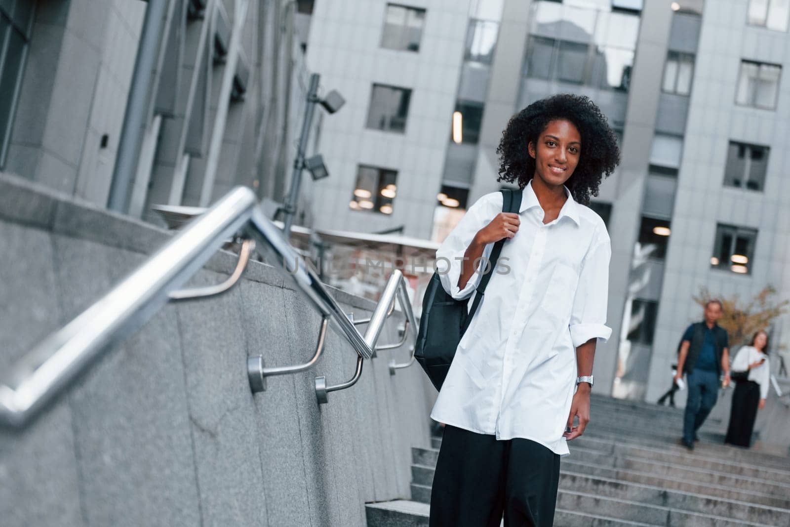 African american woman in good clothes is outdoors in the city at daytime by Standret