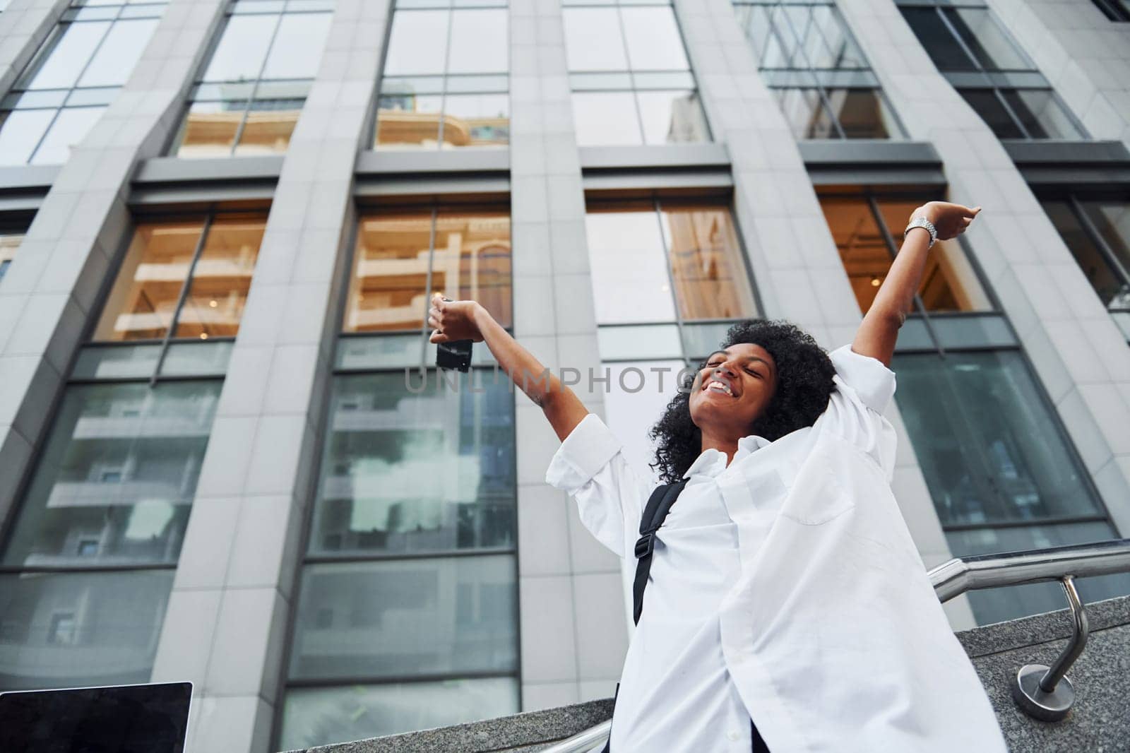 African american woman in good clothes is outdoors in the city at daytime.